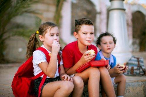 Niños comiendo frutas en el recreo.